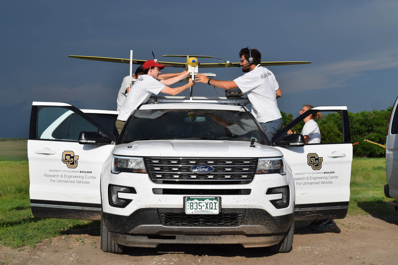 Researchers load instrumentation onto a tracker vehicle before a drone’s takeoff.